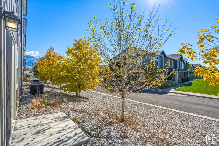 Concrete patio, gravel landscaping, exterior wall-mounted light fixture, and mature deciduous trees