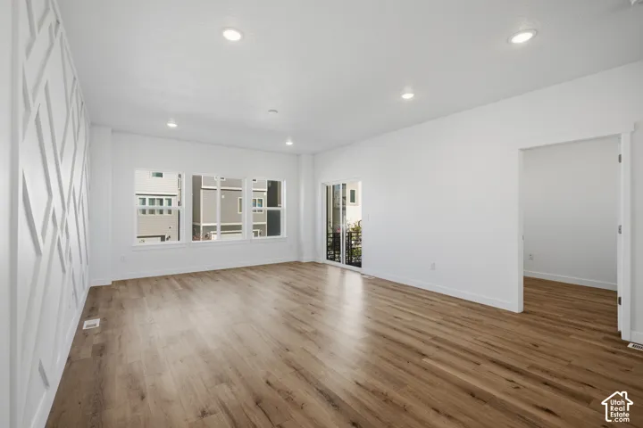 Living area featuring wood-finish flooring, recessed lighting, expansive windows, geometric wall molding, and sliding glass door access