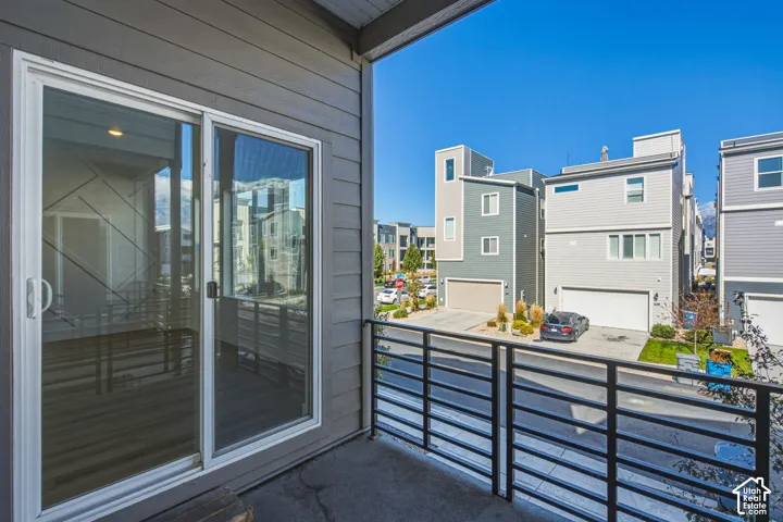 Covered balcony featuring horizontal metal railings and sliding glass door entry