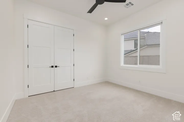 Neutral-toned carpeting, matte black ceiling fan, recessed lighting, and double doors with matte black hardware