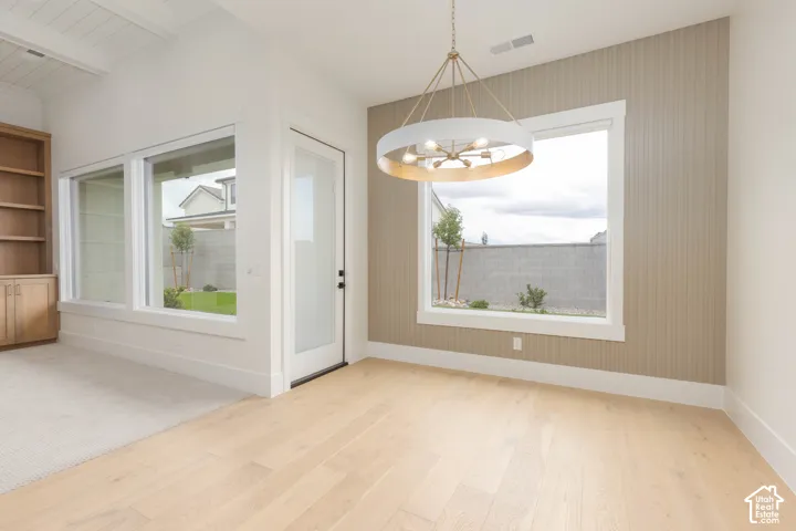 Beamed ceiling with wood-finish flooring, full-height built-in cabinetry, vertical shiplap accent wall, and a large circular multi-bulb chandelier
