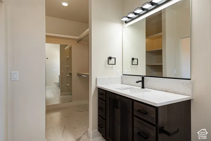 Bathroom vanity with a white countertop and integrated sink, matte black faucet, and dark wood-finish cabinetry