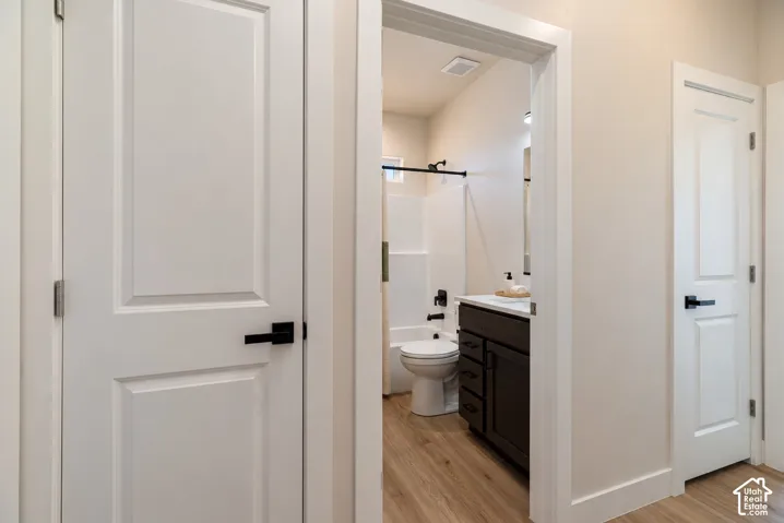 Bathroom featuring wood-finish flooring, dark cabinetry with white countertop, and matte black hardware