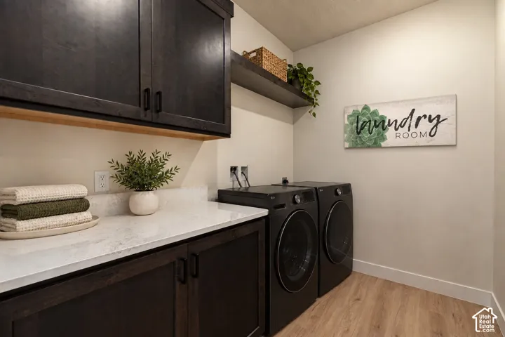 Laundry room featuring dark-stained cabinetry, light-toned stone-surface countertops, wood-finish flooring, and a built-in open shelving unit