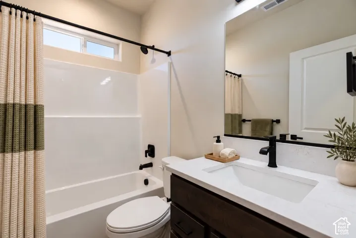 Dark-stained wood vanity with a white countertop and rectangular undermount sink, paired with a matte black faucet, wall-to-wall mirror, and a shower-tub combination featuring a white surround and matte black fixtures