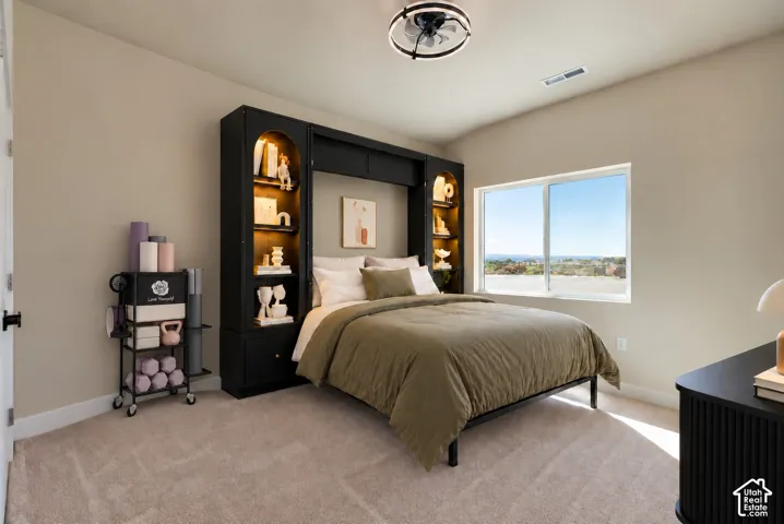 Built-in black cabinetry with arched display shelving and integrated lighting, neutral carpeting, large slider window, and circular ceiling fan fixture