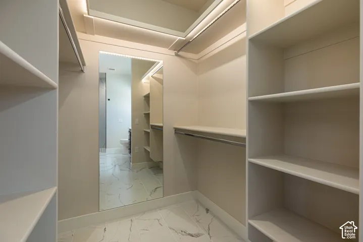 Walk-in closet featuring built-in shelving, hanging rods, full-length mirror, recessed lighting, and tile flooring