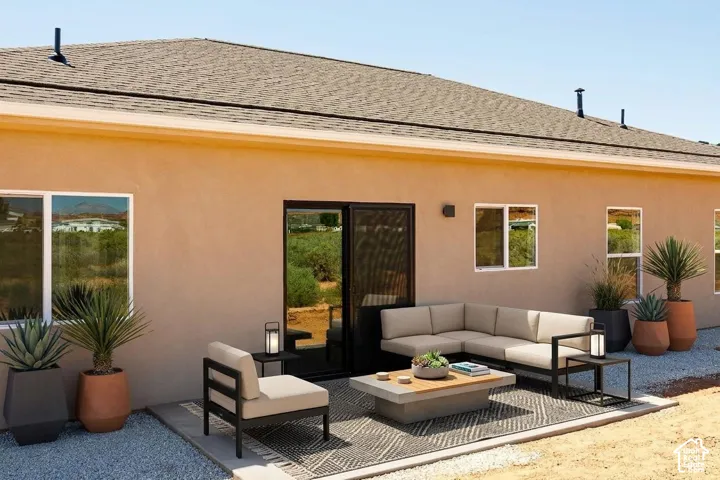 Stucco exterior with a pitched shingle roof, complemented by a concrete patio area, black-framed sliding glass door, and multiple windows