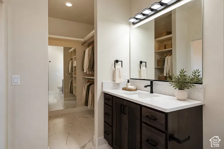 Dark wood vanity featuring a quartz countertop, rectangular undermount sink, matte black faucet, and matching hardware, finished with a large mirror, integrated wall lighting, and porcelain tile flooring