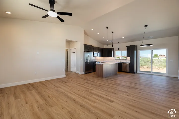 Open-concept living space featuring wood-finish flooring and vaulted ceilings