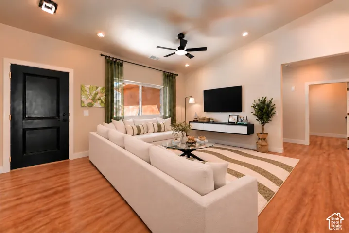 Vaulted ceilings, wood-finish flooring, recessed lighting, ceiling fan, and wall-mounted console