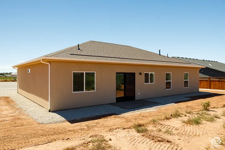 Stucco exterior with a shingle roof, complemented by white gutters and downspouts