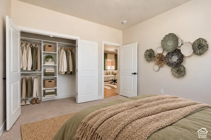 Bedroom featuring wall-to-wall carpeting, interior hinged closet doors, and built-in closet organization with shelving and hanging rods