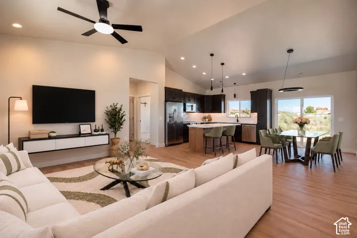 Vaulted ceilings, wood-finish flooring, kitchen island with built-in cabinetry, recessed lighting, and wall-mounted media console
