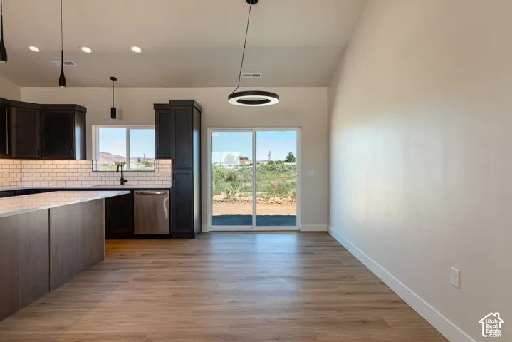 Open-concept kitchen with dark wood-finish cabinetry, white subway tile backsplash, and stainless steel appliances
