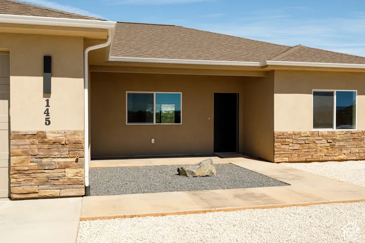 Stucco exterior with stacked stone accents, covered entry, and gravel landscaping