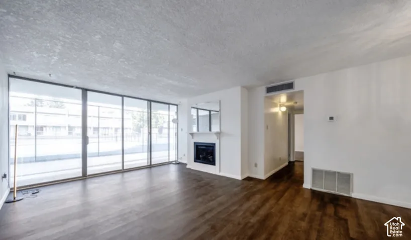 Living area featuring floor-to-ceiling glass sliding doors, wood-finish flooring, and a fireplace with a mantel-mounted mirror
