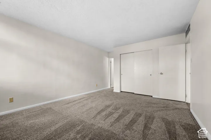 Interior room featuring neutral-toned carpeting, textured ceilings, and built-in sliding closet doors