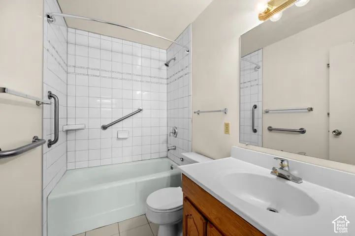 Bathroom featuring a shower and tub combination with tile surround, wood-finish cabinetry, a white countertop with an integrated basin, and chrome hardware