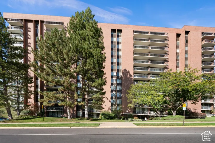 Mid-rise brick exterior featuring stacked private balconies, vertical window columns, and established landscaping