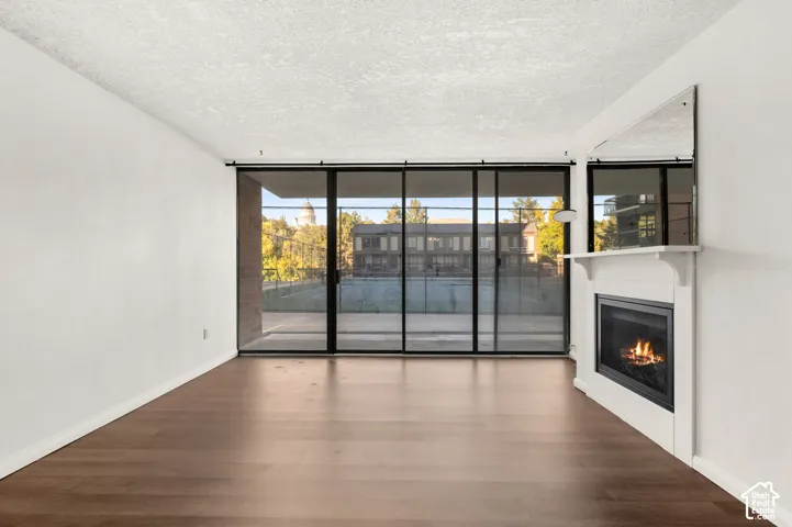 Living space featuring wood-finish flooring, floor-to-ceiling sliding glass doors, and a built-in fireplace with a white mantel and over-mantel mirror