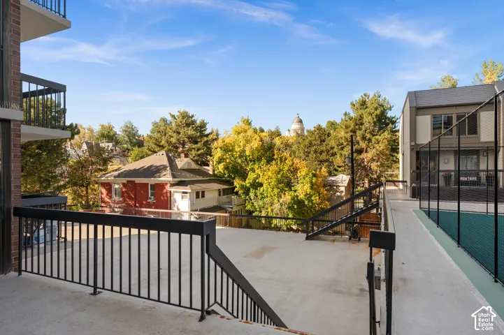 Elevated concrete deck featuring black metal railings and direct access to a fenced sports court