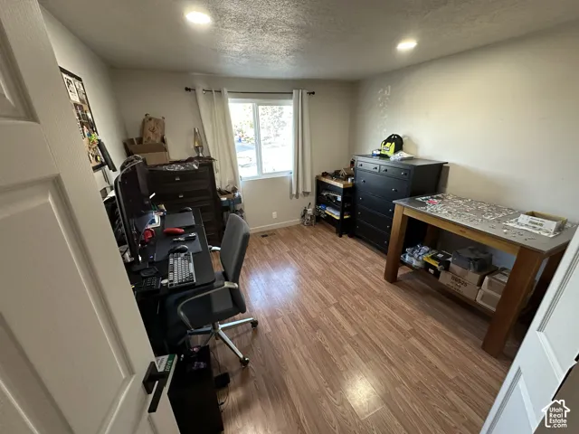 Room featuring wood-finish flooring, recessed lighting, and a single-pane window