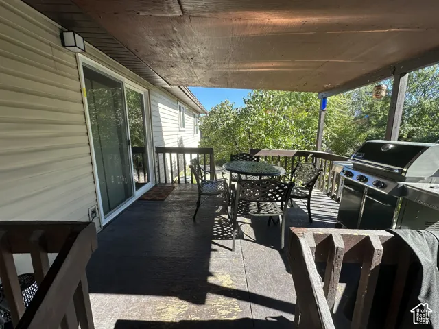 Covered deck featuring vinyl siding, vertical balustrades, and sliding glass entry door