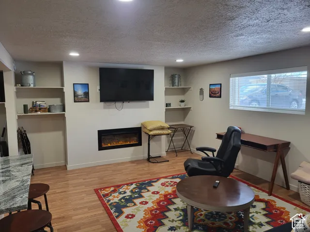 Built-in wall fireplace, wood-finish flooring, recessed lighting, and integrated shelving alcoves