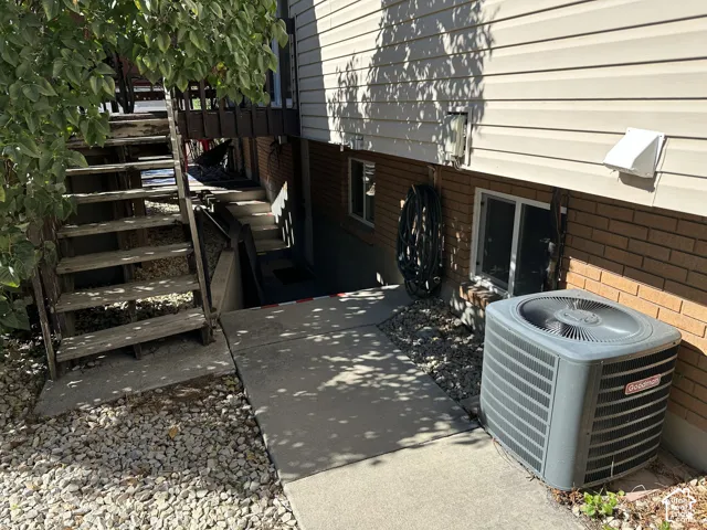 Exterior elevation featuring vinyl siding, brick masonry, concrete walkway, and ground-mounted HVAC unit