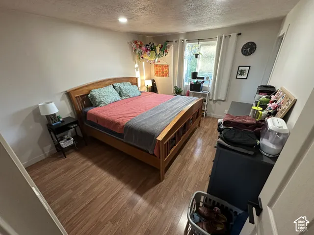 Room featuring wood-finish flooring, recessed lighting, and a window with neutral-toned curtains