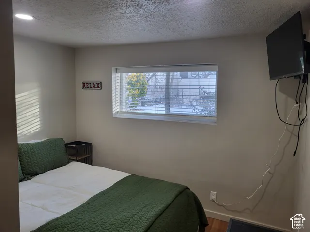 Room featuring recessed lighting, a sliding window with horizontal blinds, and wood-finish flooring