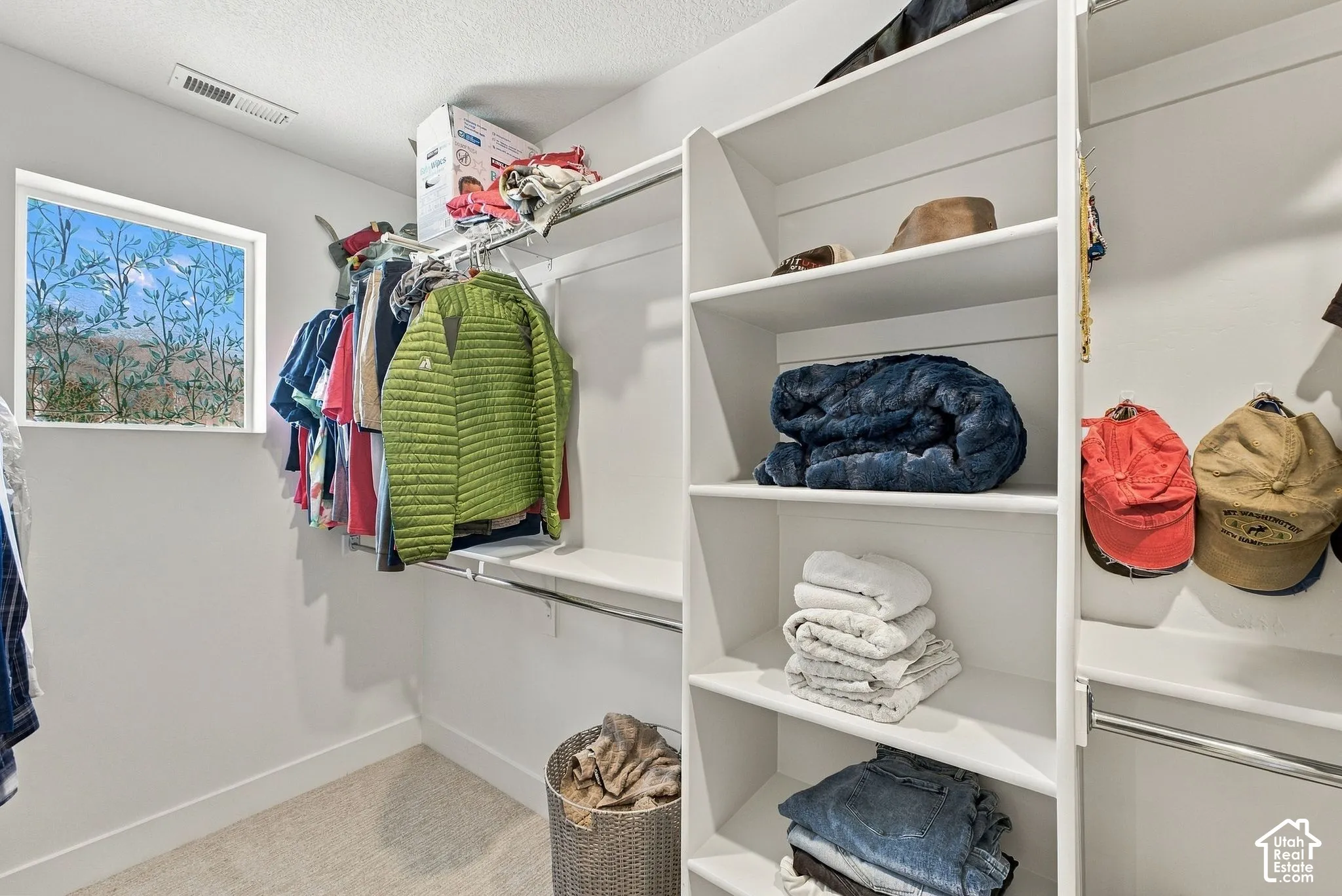 Walk-in closet featuring white built-in shelving, integrated hanging rods, and a window