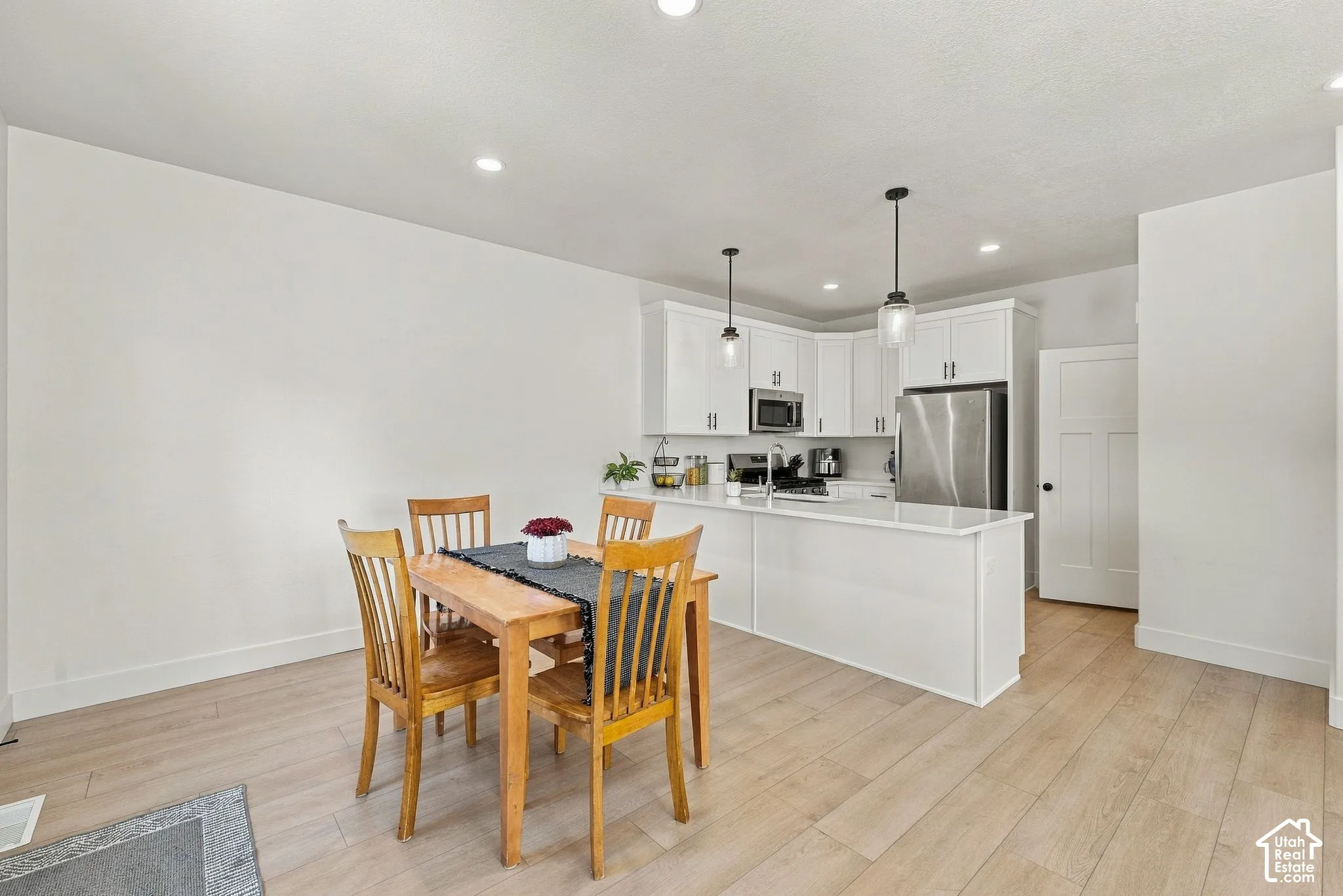 Kitchen area featuring white cabinetry, a peninsula with stone-surface countertops, recessed lighting, and wood-finish flooring