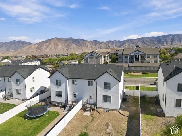 Multi-story residence featuring a white stucco exterior, dark shingle roofing, and mountain range backdrop
