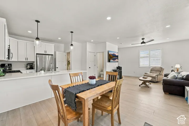 Open-concept living space featuring wood-finish flooring, white shaker-style cabinetry, a quartz kitchen island, recessed lighting, and suspended pendant fixtures