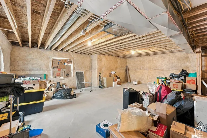 Unfinished basement with exposed wooden ceiling joists, concrete flooring, insulation-wrapped walls, and exposed ductwork