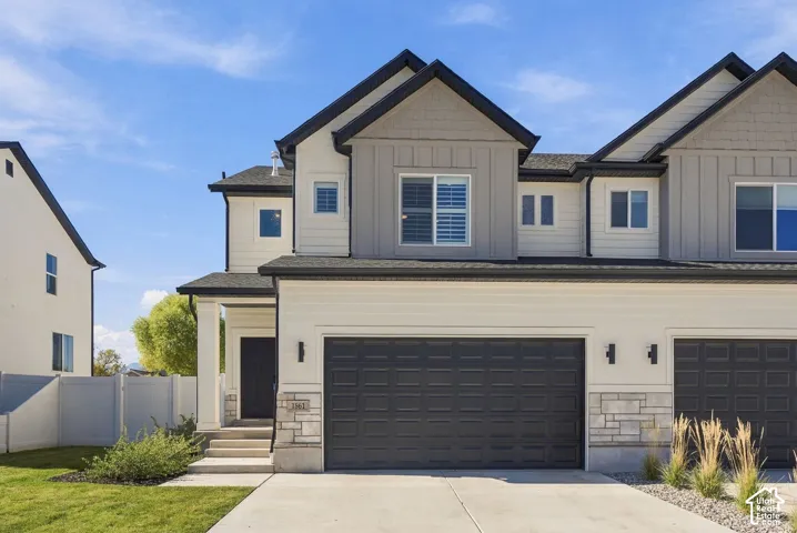 Multi-level exterior featuring a combination of horizontal lap siding and vertical board-and-batten siding, stone veneer accents, an attached two-car garage, and dual-gabled rooflines
