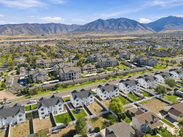 Aerial perspective of a suburban neighborhood featuring multi-level residential structures, fenced private rear yards, and a backdrop of mountain scenery