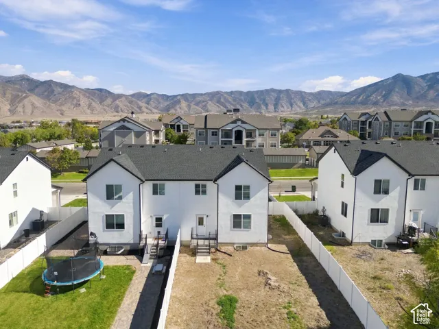 Aerial perspective featuring white stucco exterior buildings with dark shingle roofing, enclosed rear yards, and mountain backdrop