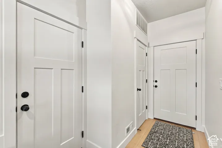 Interior space featuring white-painted three-panel doors with matte black hardware, light-toned wood-finish flooring, and crisp white wall trim