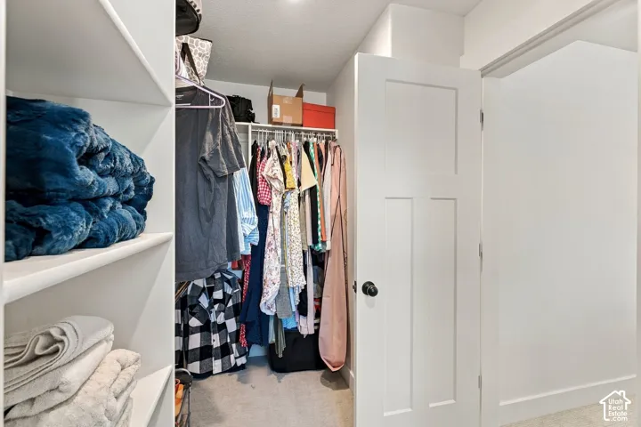 Walk-in closet featuring white built-in shelving, integrated hanging rods, and a three-panel interior door with matte black hardware