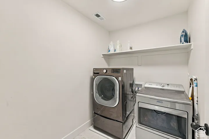 Dedicated laundry area featuring a white built-in storage shelf and neutral hard-surface flooring
