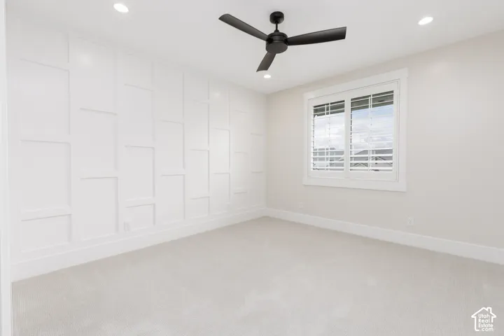 Accent wall with wainscoting detail, matte black ceiling fan, recessed lighting, and plantation shutters