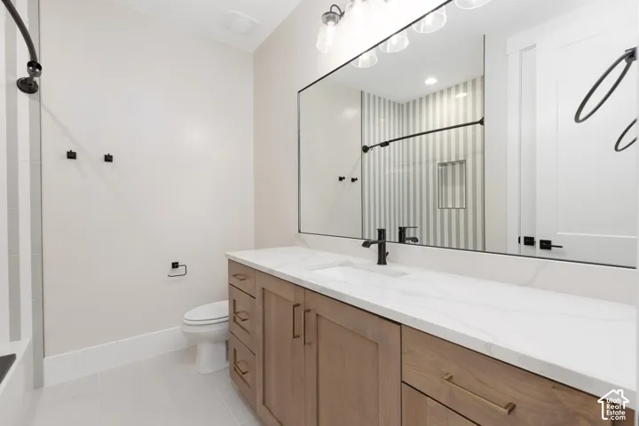 Bathroom featuring a vanity with wood-finish cabinetry, quartz countertop, an integrated rectangular sink, matte black hardware, and a large wall-mounted mirror