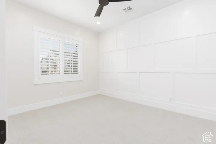 Room featuring crisp board-and-batten wall detailing, white plantation shutters, neutral carpeting, recessed lighting, and a modern ceiling fan