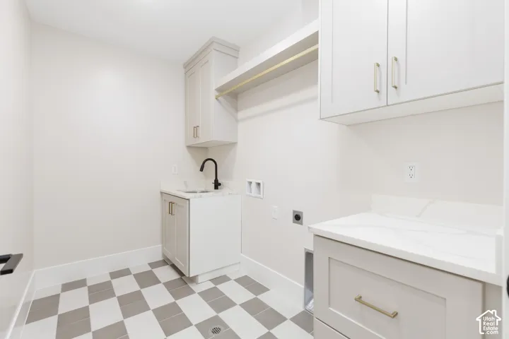 Utility room featuring light-toned cabinetry, stone-finish countertops, matte black faucet, integrated sink, and checkerboard tile flooring