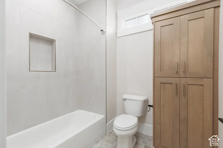 Full-height wood-finish cabinetry, porcelain tile tub surround with integrated wall niche, and transom window