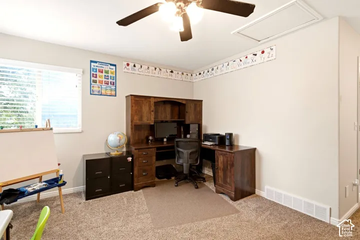 Neutral wall tones, carpeted flooring, window with horizontal blinds, and a multi-blade ceiling fan with integrated lighting