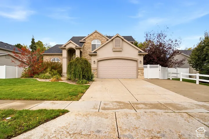 Exterior featuring a stone and stucco facade, arched entryway, and a two-car attached garage with a concrete driveway